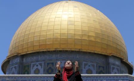 Palestinian woman prays in front of the Dome of the Rock on the first Friday of the holy month of Ramadan at the compound known to Muslims as the Noble Sanctuary and to Jews as Temple Mount, in Jerusalem's Old City June 19, 2015. REUTERS/Ammar Awad/Files