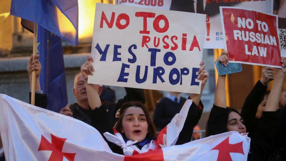 Protesters in Georgia hold signs in protest at the draft bill on foreign agents