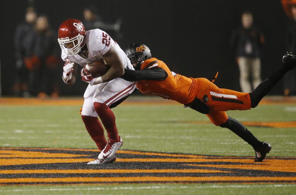 Oklahoma running back Joe Mixon (25) gets away from Oklahoma State safety Tre Flowers (31) during an NCAA college football game between Oklahoma and Okalhoma State in Stillwater, Okla., Monday, Nov. 30, 2015. Oklahoma won 58-23. (AP Photo/Sue Ogrocki)