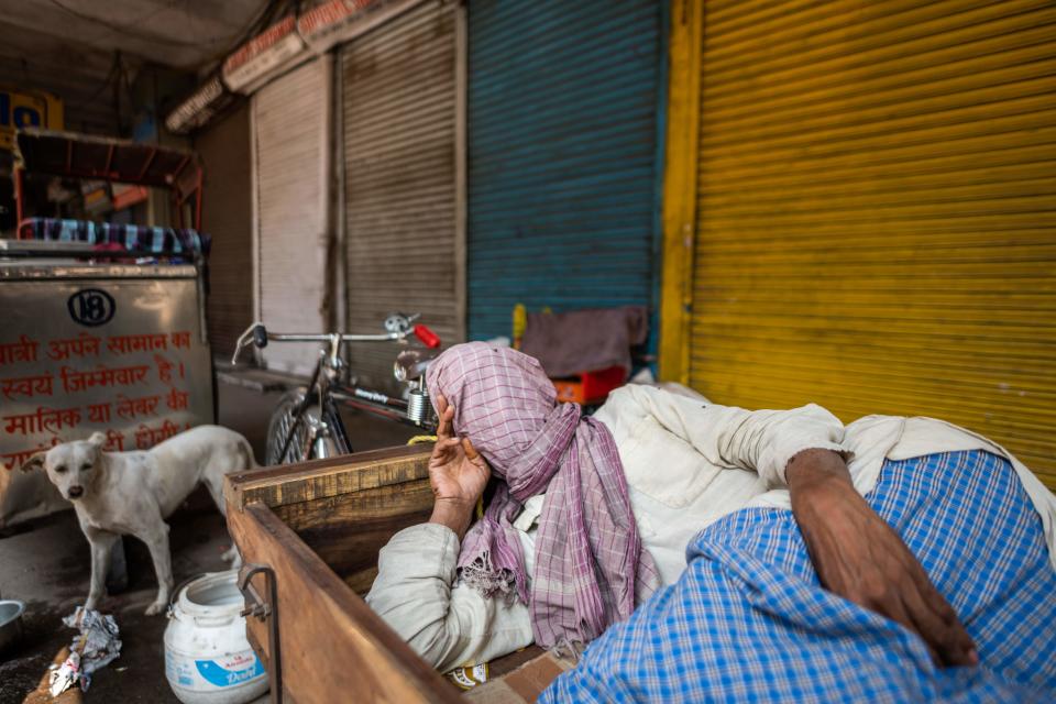 A man takes a nap laying on a rickshaw-van in front of closed shops during a one-day nationwide Janata (civil) curfew imposed as a preventive measure against the COVID-19 coronavirus, in the old quarters of New Delhi on March 22, 2020. - Nearly one billion people around the world were confined to their homes, as the coronavirus death toll crossed 13,000 and factories were shut in worst-hit Italy after another single-day fatalities record. (Photo by Jewel SAMAD / AFP) (Photo by JEWEL SAMAD/AFP via Getty Images)