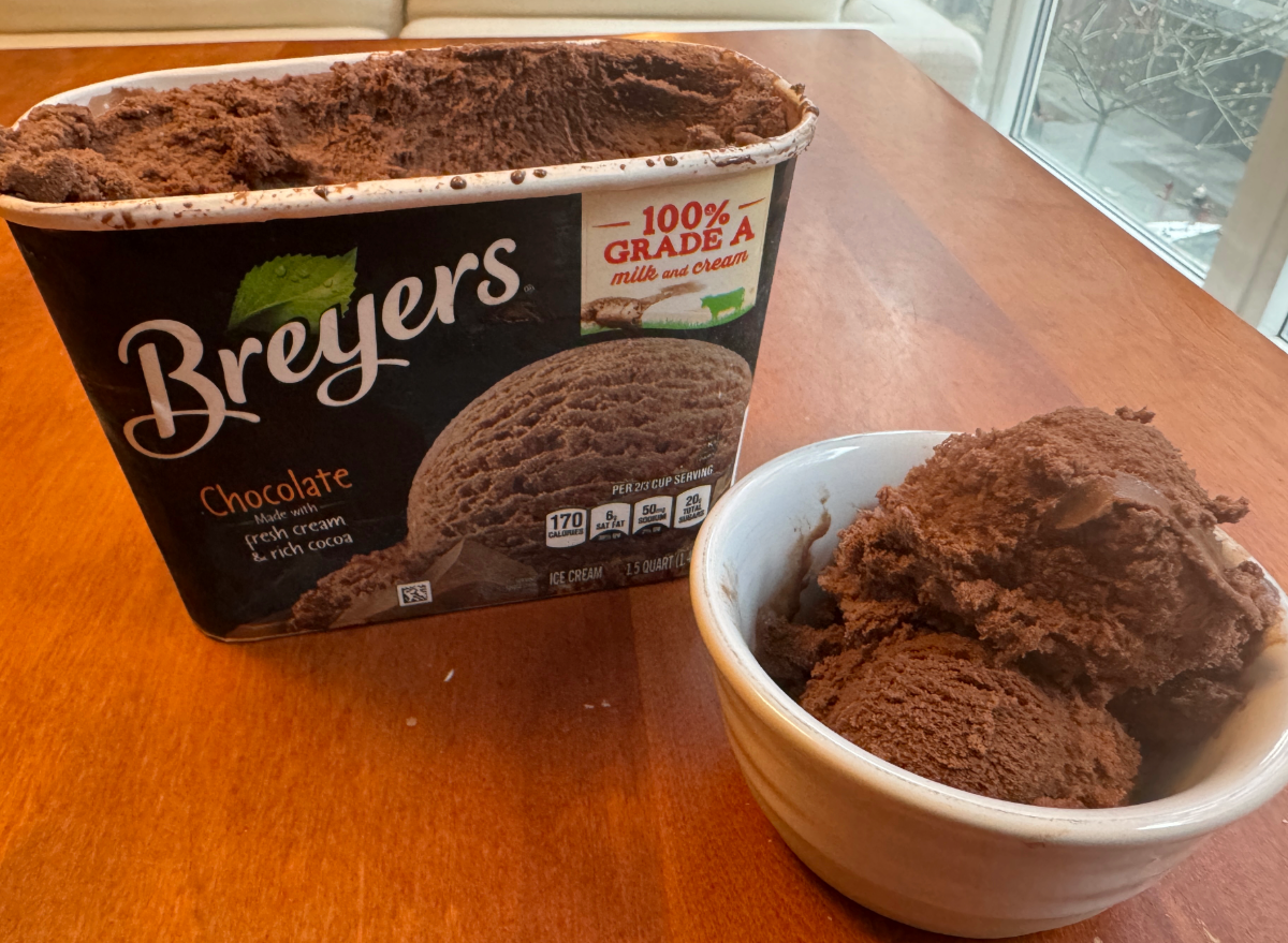 breyers chocolate ice cream in an open container and a bowl on a table. 