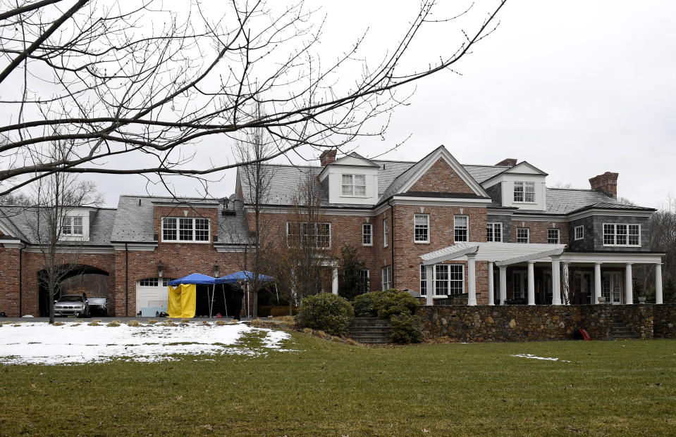 A yellow tarp is set up and watched over by a police officer outside of the garage to Fotus Dulos' home, Tuesday, Jan. 28, 2020, in Farmington, Conn. A dispatcher from the Farmington police said officers had responded to Dulos' home and he was later transported to the hospital (AP Photo/Jessica Hill)