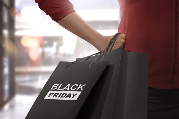 A woman holds a Black Friday shopping bag.
