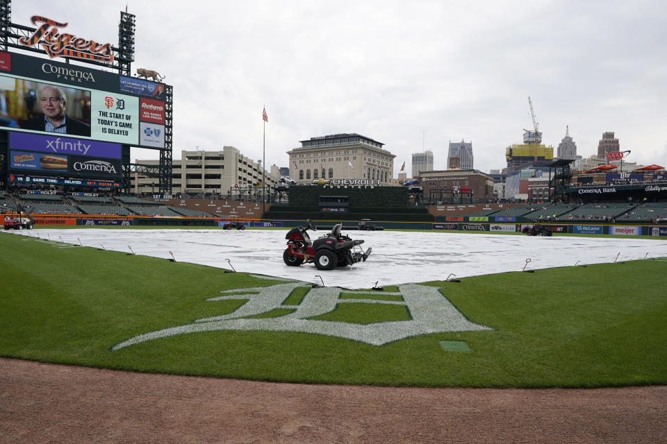A tarp covers the field at Comerica Park as fans wait for the start of the baseball game between the Detroit Tigers and the San Francisco Giants, Sunday, April 16, 2023, in Detroit. (AP Photo/Carlos Osorio)