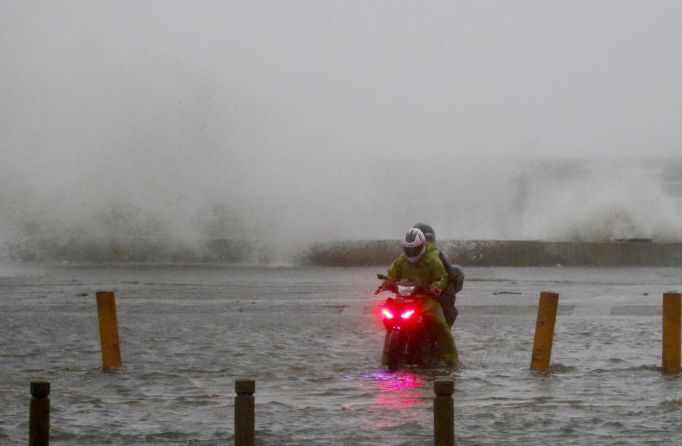 A motorist braves the rain and strong winds brought about by Typhoon Mangkhut which barreled into northeastern Philippines before dawn Saturday, Sept. 15, 2018 in Manila, Philippines. The typhoon slammed into the Philippines' northeastern coast early Saturday, its ferocious winds and blinding rain ripping off tin roof sheets and knocking out power, and plowed through the agricultural region at the start of the onslaught. (AP Photo/Bullit Marquez)