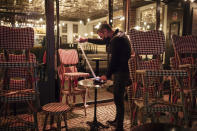 A waiter checks the final revenue as he closes a bar terrace in Paris, Saturday, Oct. 17, 2020. French restaurants, cinemas and theaters are trying to figure out how to survive a new curfew aimed at stemming the flow of record new coronavirus infections. The monthlong curfew came into effect Friday at midnight, and France is deploying 12,000 extra police to enforce it. (AP Photo/Lewis Joly)