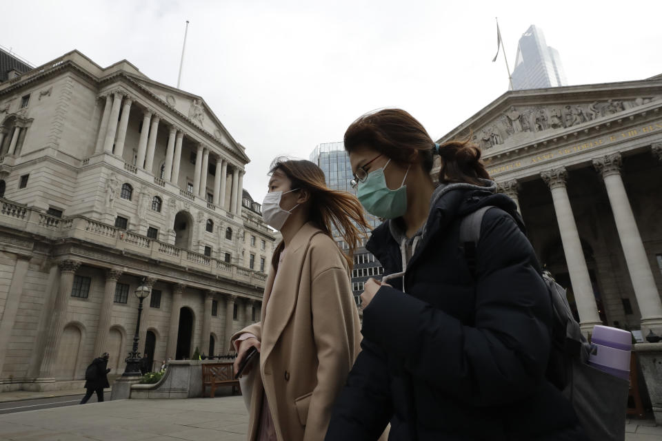 Pedestrians wearing face masks walk past the Bank of England in London, Wednesday, March 11, 2020. Britain's Chancellor of the Exchequer Rishi Sunak will announce the first budget since Britain left the European Union. (AP Photo/Matt Dunham)