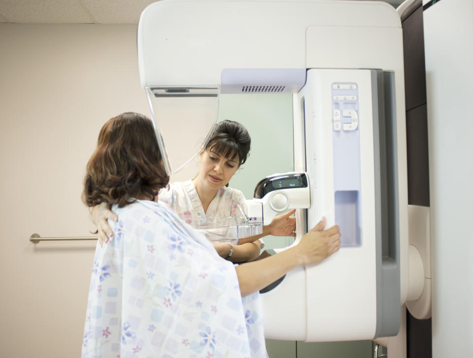 A healthcare worker assists a patient with a mammogram