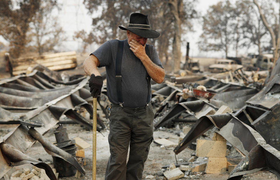 Ed Bledsoe tries to hold back tears as he searches through what remains of his home, Monday, Aug. 13, 2018, in Redding, Calif. Bledsoe's wife, Melody, great-grandson James Roberts and great-granddaughter Emily Roberts were killed at the home in the Carr Fire. (AP Photo/John Locher)