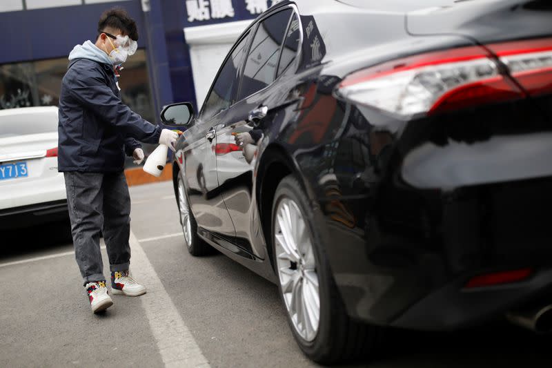 Staff member disinfects a vehicle at a service centre of car-hailing service Didi Chuxing, as the country is hit by an outbreak of the new coronavirus, in Beijing