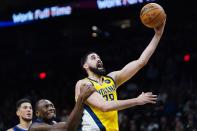 Indiana Pacers center Goga Bitadze, right, is fouled by Phoenix Suns center Bismack Biyombo, center, as Suns guard Devin Booker, left, looks on during the first half of an NBA basketball game Saturday, Jan. 22, 2022, in Phoenix. (AP Photo/Ross D. Franklin)