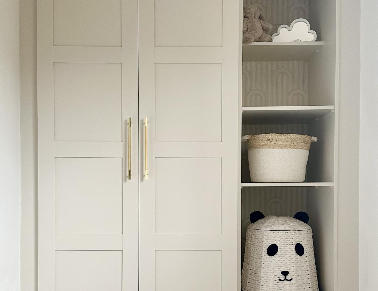  An IKEA PAX closet painted a cream color with open shelving decorated with kids' toys and baskets. 