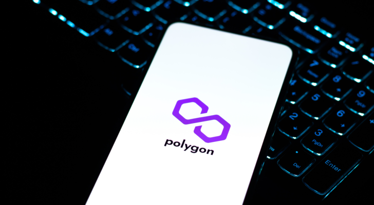 A phone, on top of a laptop keyboard, displaying the logo for Polygon (MATIC-USD)