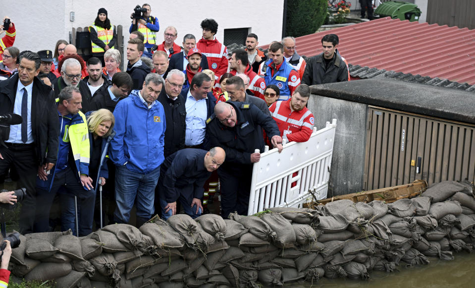 German Federal Chancellor Olaf Scholz, foreground centre right, Bavarian Prime Minister Markus S'der, foreground centre left, Bavarian Interior Minister Joachim Herrmann, centre, German Federal Interior Minister Nancy Faeser, third left, stand behind a barrier of filled sandbags during a site inspection in Reichertshofen, Upper Bavaria, Germany, Monday, June 3, 2024, after flooding in the area. (Sven Hoppe/dpa via AP)