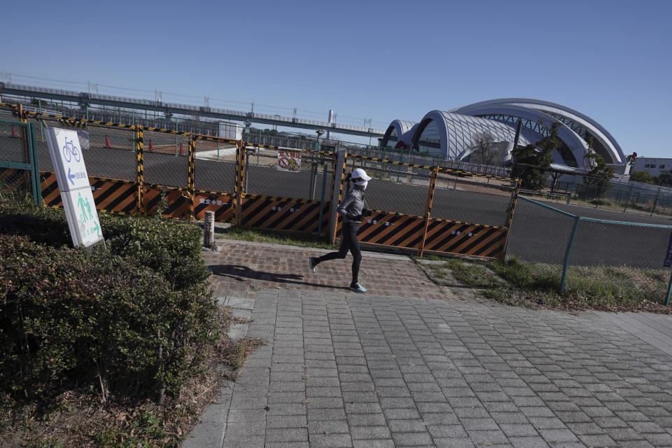 A woman runs near Tokyo Tatsumi International Swimming Center, one of the venues of Tokyo 2020 Olympic and Paralympic games, in Tokyo Wednesday, Jan. 20, 2021. The postponed Tokyo Olympics are to open in just six months. Local organizers and the International Olympic Committee say they will go ahead on July 23. But it’s still unclear how this will happen with virus cases surging in Tokyo and elsewhere around the globe. (AP Photo/Eugene Hoshiko)