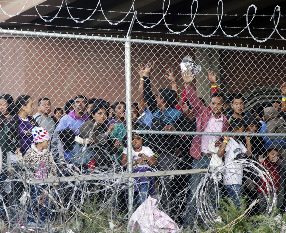 FILE - In this March 27, 2019, file photo, Central American migrants wait for food in a pen erected by U.S. Customs and Border Protection to process a surge of migrant families and unaccompanied minors in El Paso, Texas. Attorneys on Friday, Aug. 30, 2019, asked a judge to reject Trump administration plans to detain migrant families longer than they're allowed now and to remove court oversight of how children are treated in government custody. (AP Photo/Cedar Attanasio, File)