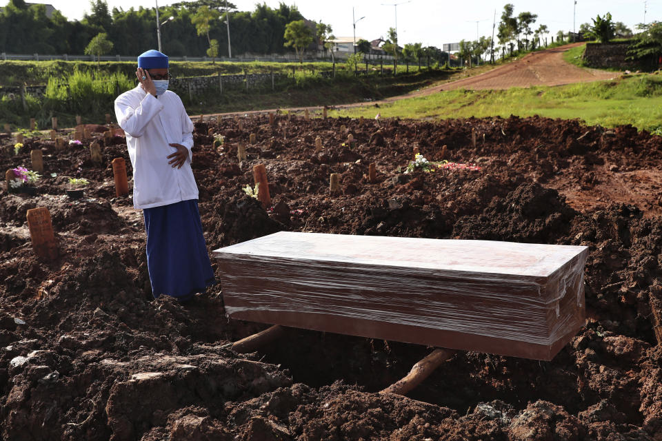 An Islamic cleric recites the call of prayer during the burial of a man at the special section of Jombang Public Cemetery reserved for those who died of COVID-19, in Tangerang on the outskirts of Jakarta, Indonesia,Monday, June 21, 2021. Indonesia saw significant spikes in confirmed COVID-19 cases recently, an increase blamed on travel during last month's Eid al-Fitr holiday as well as the arrival of new virus variants, such as the the Delta version first found in India. (AP Photo/Tatan Syuflana)