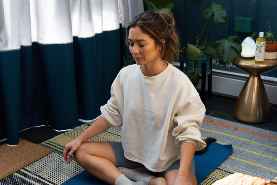 Emma Lovewell at home meditating on a yoga mat