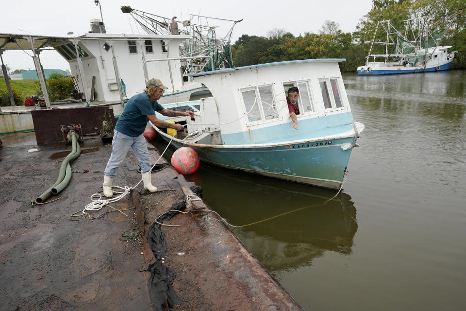 Perry Menesses tosses a rope to Will Guillot as they wanted to secure their boat with more rope after hearing that Hurricane Zeta has increased in strength, in Violet, La., Wednesday, Oct. 28, 2020. Hurricane Zeta is expected to make landfall this afternoon as a category 2 storm. (AP Photo/Gerald Herbert)