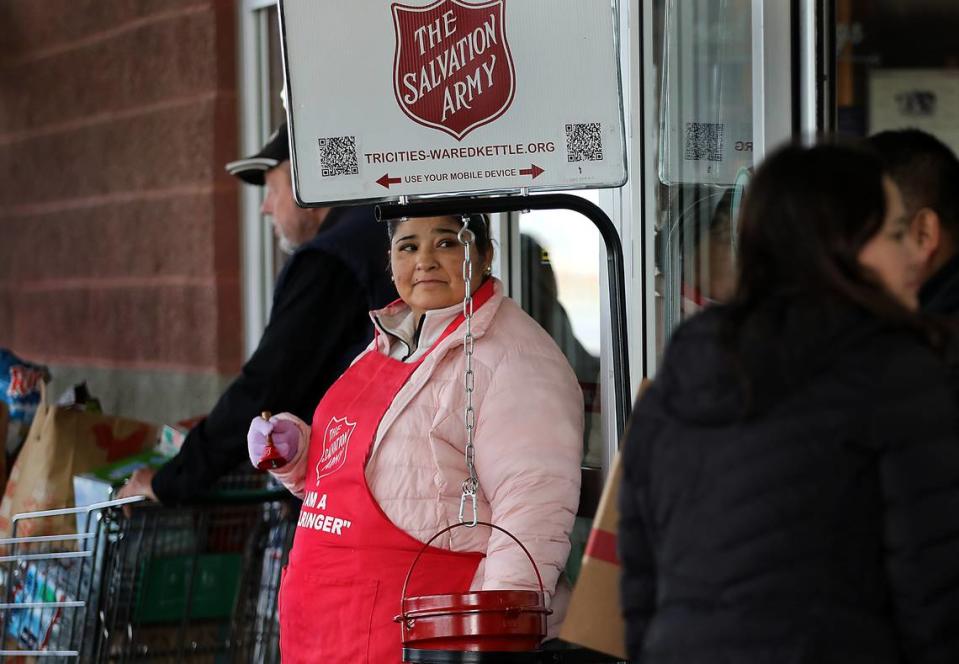 Susan Frankl of Pasco puts a donation into a Red Kettle as Salvation Army bellringer Consuelo Luna stands inside the entryway to a grocery store on Road 68 in west Pasco. There’s a shortage of bellringers this year.