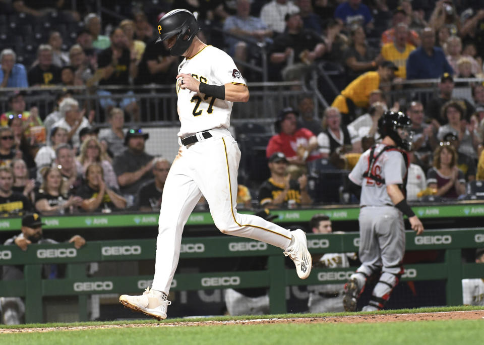 The Pittsburgh Pirates' Kevin Newman (27) scores on a wild pitch by Cincinnati Reds Graham Ashcraft as catcher Michael Papierski (26) goes after the ball during the sixth inning of a baseball game Friday, Aug. 19, 2022, in Pittsburgh. (AP Photo/Philip G. Pavely)