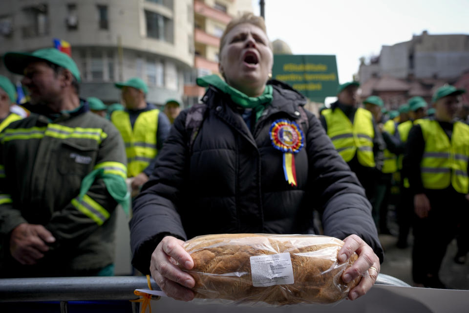 FILE - A woman holds a loaf of bread during a farmers' protest in front of the Representative Office of the European Commission in Bucharest, Romania, on, April 7, 2023. Slovakia has become the third European Union country to ban food imports from Ukraine. The move deepens a challenge for the bloc as it works to help Ukraine transport its grain to world markets. Slovakia followed Poland and Hungary, both of which announced bans Saturday on Ukrainian food imports through June 30. They did so in response to rising anger from farmers who say that a glut of grain in their countries is causing them economic hardship. (AP Photo/Andreea Alexandru, File)