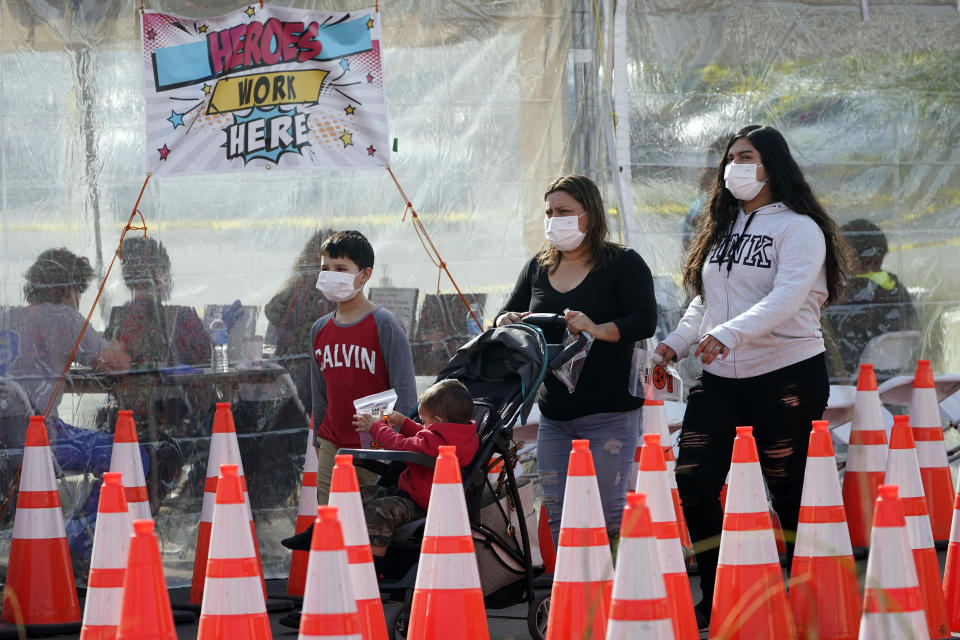 People walk past a covered tent at a COVID-19 walk-up testing site on the Martin Luther King Jr. Medical Campus Thursday, Jan. 7, 2021, in Los Angeles. (AP Photo/Marcio Jose Sanchez)