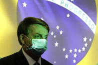 Brazil's President Jair Bolsonaro wears a mask amid the COVID-19 pandemic at the start of a ceremony where his nation's flag is projected in Brasilia, Brazil, Wednesday, Aug. 5, 2020. (AP Photo/Eraldo Peres)