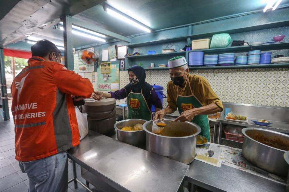 Khamis Majid packs food for a customer at Restoran Noor in Kuala Lumpur June 14, 2021. — Picture by Yusof Mat Isa