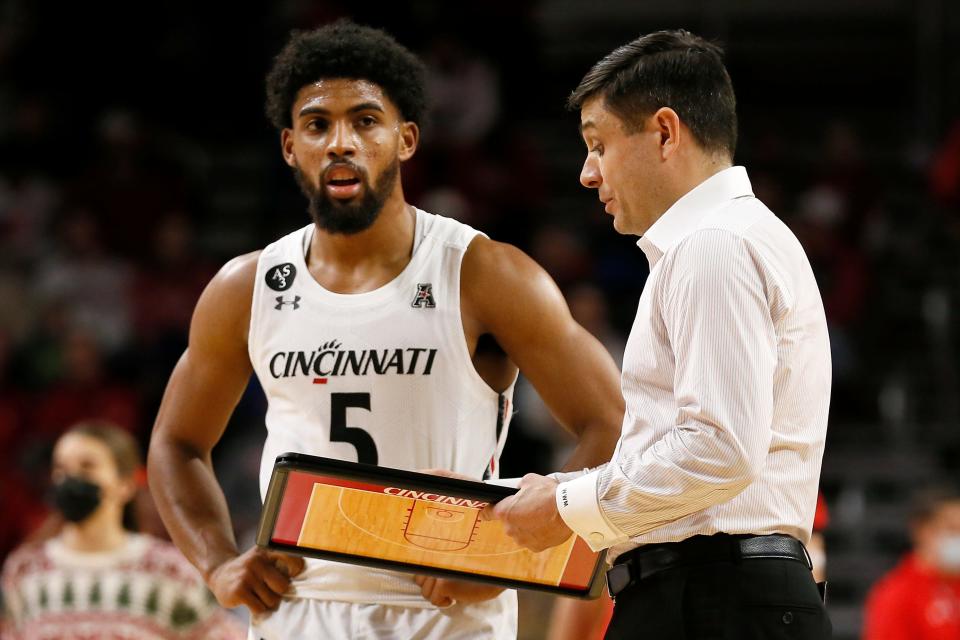 Cincinnati Bearcats head coach Wes Miller talks with guard David DeJulius (5) during a timeout in the second half of the NCAA basketball game between the Cincinnati Bearcats and the Tennessee Tech Golden Eagles at Fifth Third Arena in Cincinnati on Tuesday, Dec. 21, 2021. Cincinnati finished its non-conference schedule with a 76-67 win over the Golden Eagles.