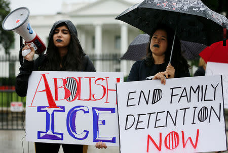 Demonstrators Madvhi Venkatraman and Gabi Huesca listen to the cries of illegal immigrant children held in a U.S. detention facility after being separated from their parents that Venkatraman is playing through her megaphone during a protest against the separation of immigrant families outside the White House in Washington, U.S., June 22, 2018. REUTERS/Jim Bourg