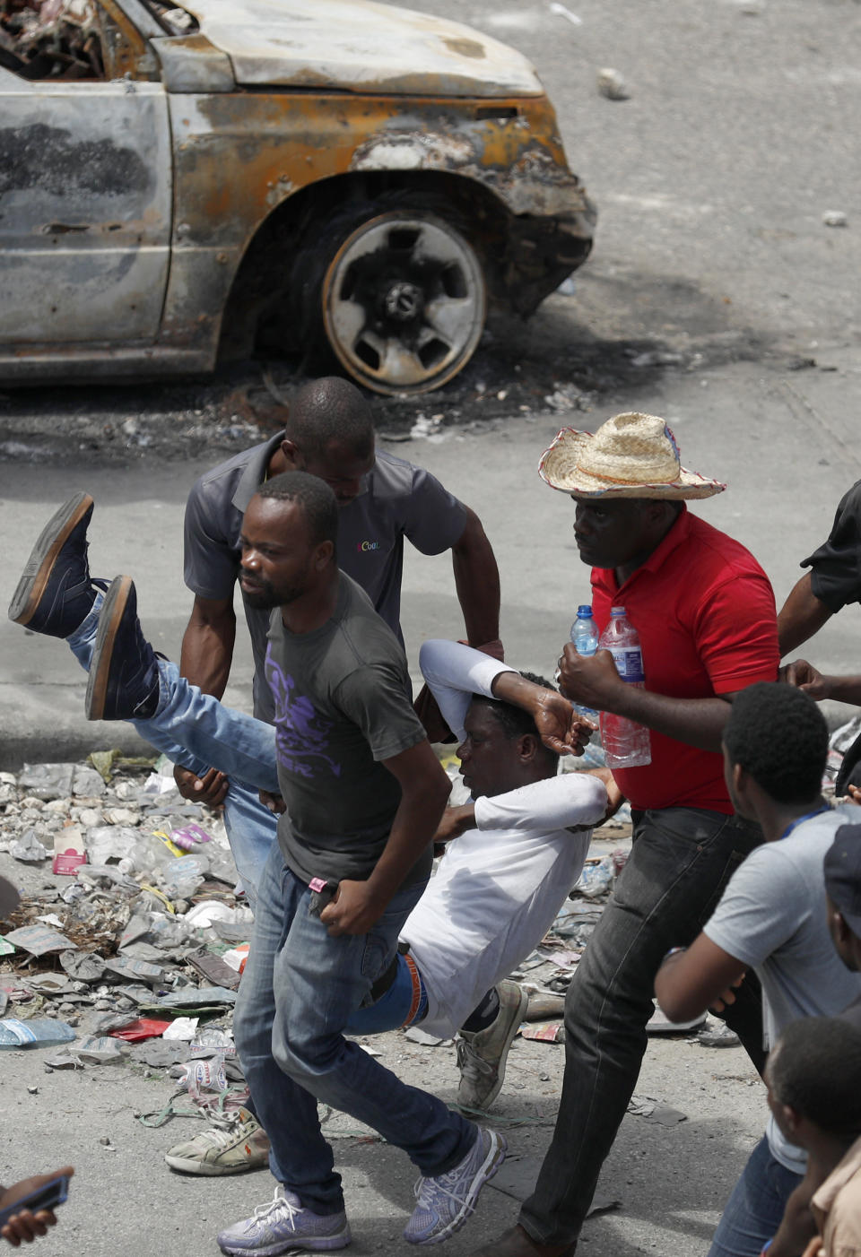 A wounded demonstrator is carried to safety during a protest calling for the resignation of President Jovenel Moise, in Port-au-Prince, Haiti, Friday, Oct. 4, 2019. After a two-day respite from the recent protests that have wracked Haiti's capital, opposition leaders urged citizens angry over corruption, gas shortages, and inflation to join them for a massive protest march to the local headquarters of the United Nations. (AP Photo/Rebecca Blackwell)