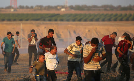 Palestinian demonstrators run as tear gas was fired by Israeli troops during a protest at the Israel-Gaza border, in the southern Gaza Strip July 27, 2018. REUTERS/Ibraheem Abu Mustafa