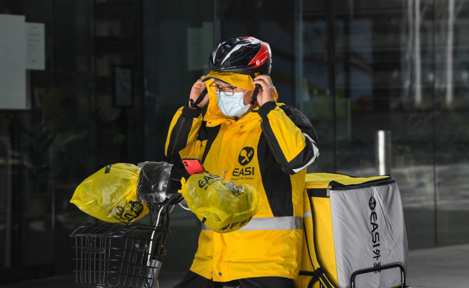 A food delivery cyclist puts on their helmet before delivery in Sydney, Australia. 