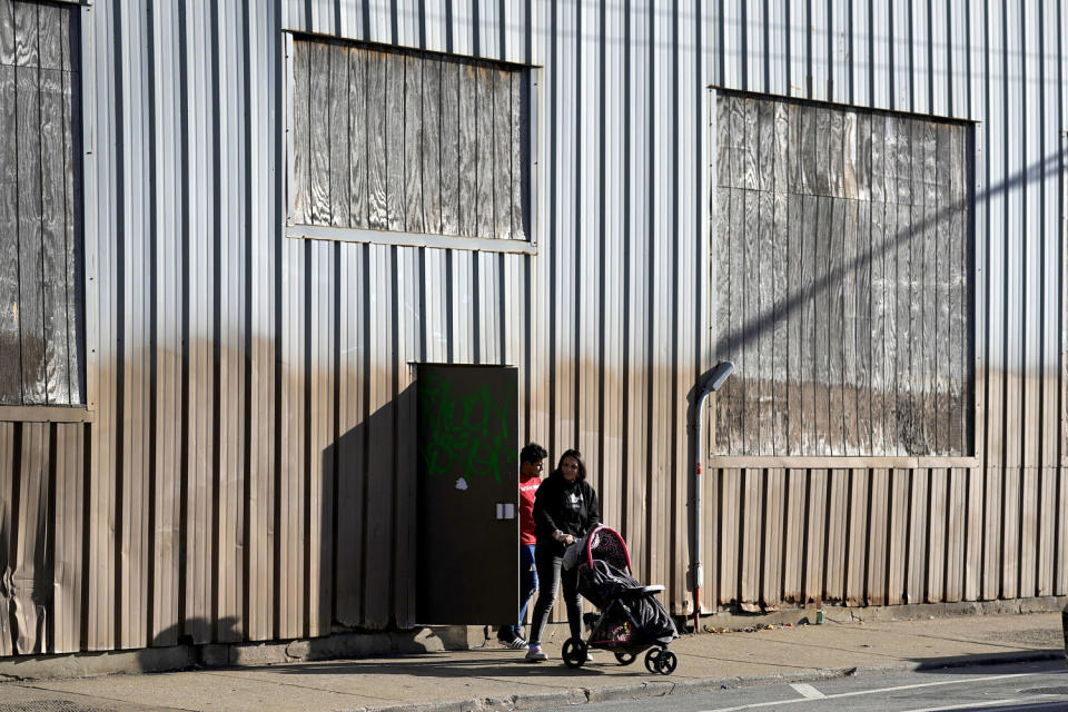 A couple and a young child leave an immigrant shelter in the Pilsen neighborhood of Chicago, on Dec. 19, 2023.  (Charles Rex Arbogast / AP)