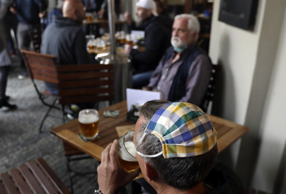 A man, wearing his face mask on top of his head, drinks a beer at a restaurant terrace in Prague, Czech Republic, Monday, May 11, 2020.Bars, restaurants, cafes offering outdoor seating started to serve their first consumers since March 14, as the Czech Republic is taking a step to normalcy amid the coronavirus pandemic by easing more restrictions adopted by the government to contain it. Interiors of the restaurants still remain closed. (AP Photo/Petr David Josek)