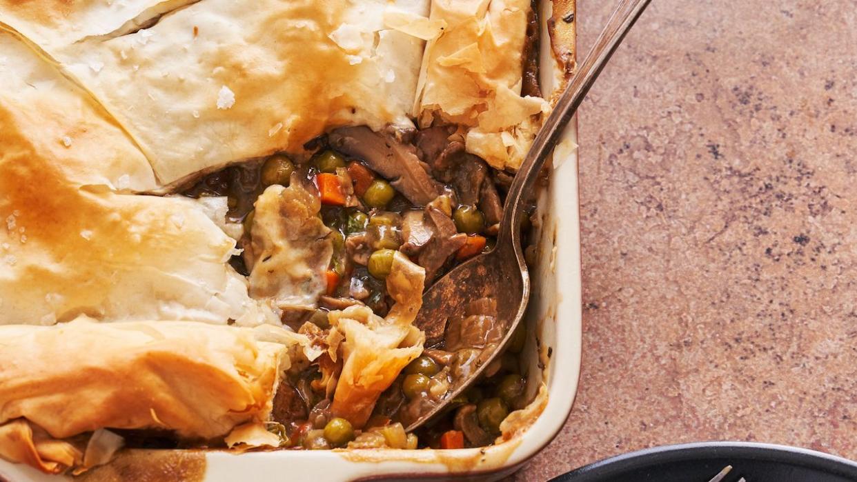 saucy vegan mushroom pot pie with phyllo dough crust, first portion scooped onto a plate