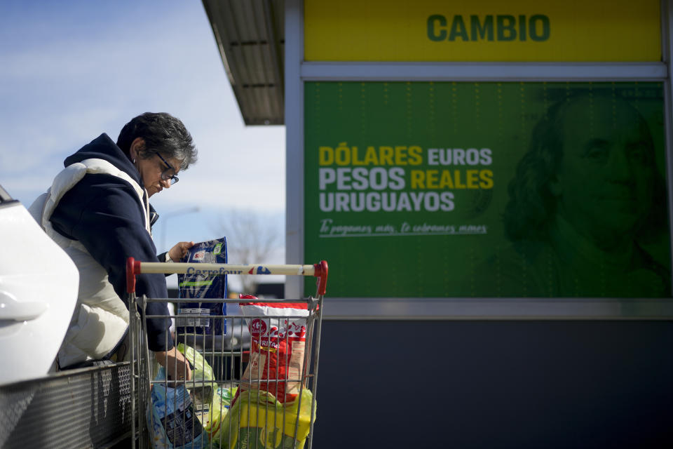 Uruguayan Consuelo Ramirez, a social worker, unloads her shopping cart outside a super market where a currency exchange shop is open for business in Gualeguaychu in the province of Entre Rios, Argentina, a few kilometers from the Uruguayan border, Friday, June 30, 2023. Uruguayans buy U.S. dollars in Uruguay, then bring those dollars across the border into Argentina, where they use them to buy Argentina pesos on the black market at almost double the official exchange rate. (AP Photo/Natacha Pisarenko)