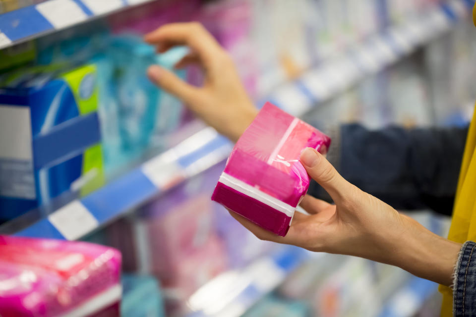 A hand holds pads in an aisle at the store