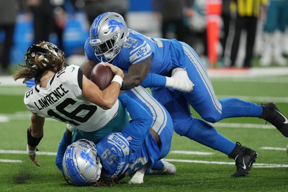 Jaguars quarterback Trevor Lawrence (16) is sacked by Lions linebacker James Houston (59) and defensive end Josh Paschal during the first half Sunday, Dec. 4, 2022, in Detroit.