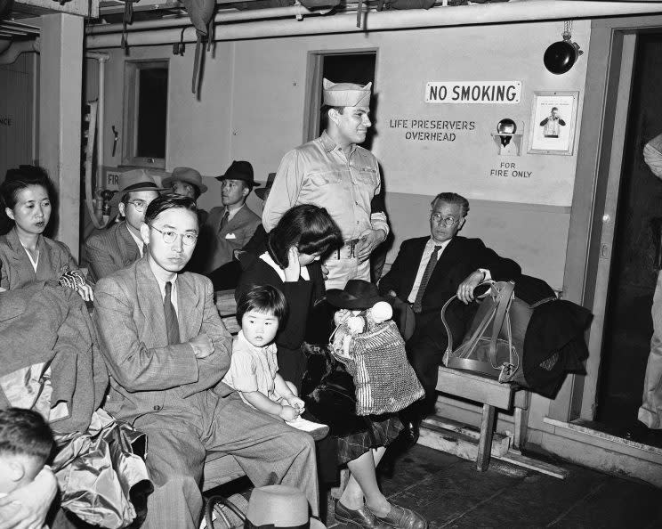 A guard stands among Japanese nationals en route to Ellis Island on a harbor boat after they arrived in New York, Aug. 11, 1945, on the S.S. Santa Rosa from Europe. They are part of 158 Japanese nationals slated for internment as enemy aliens. (Photo: Matty Zimmerman/AP)