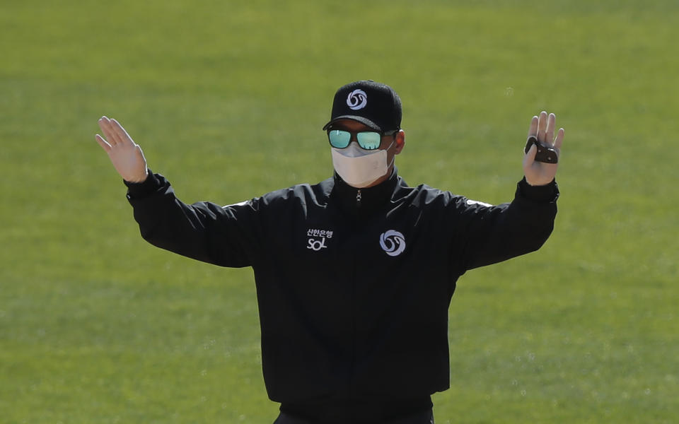 First base umpire Lee Gye-sung wearing a mask and gloves as a precaution against the new coronavirus calls during the pre-season baseball game between Doosan Bears and LG Twins in Seoul, South Korea, Tuesday, April 21, 2020. South Korea's professional baseball league has decided to begin its new season on May 5, initially without fans, following a postponement over the coronavirus. (AP Photo/Lee Jin-man)