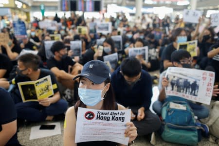 Anti-extradition bill protesters hold up placards for arriving travellers during a protest at the arrival hall of Hong Kong International Airport