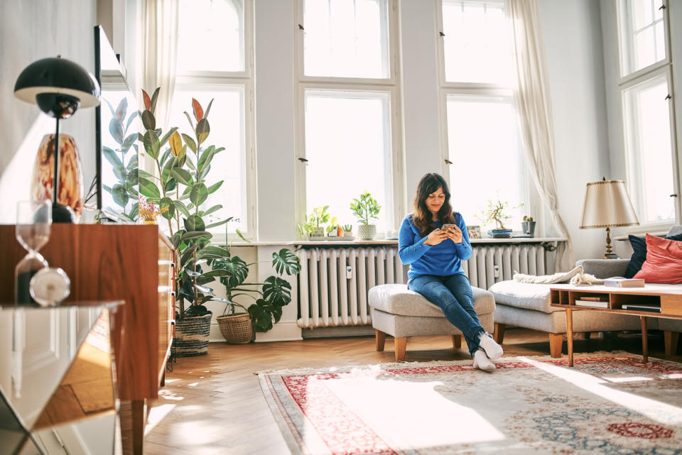 This woman sits on her ottoman that doubles as a convenient living room storage space. 