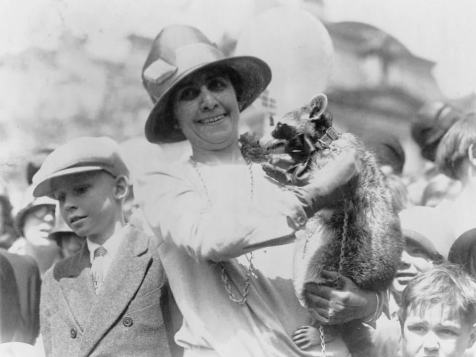 First lady Grace Coolidge displays her pet raccoon, Rebecca, for a crowd of children at the 1927 White House Easter Egg Roll.