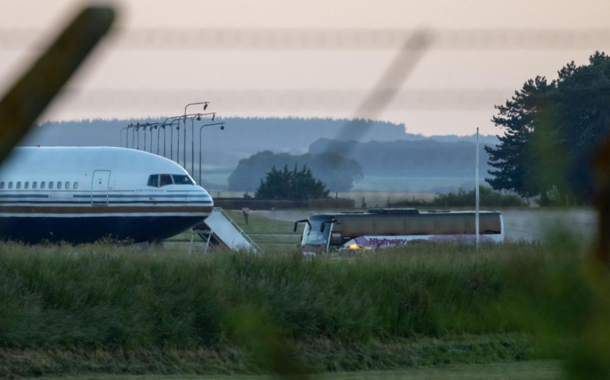 A coach pulls up by a Rwanda deportation flight