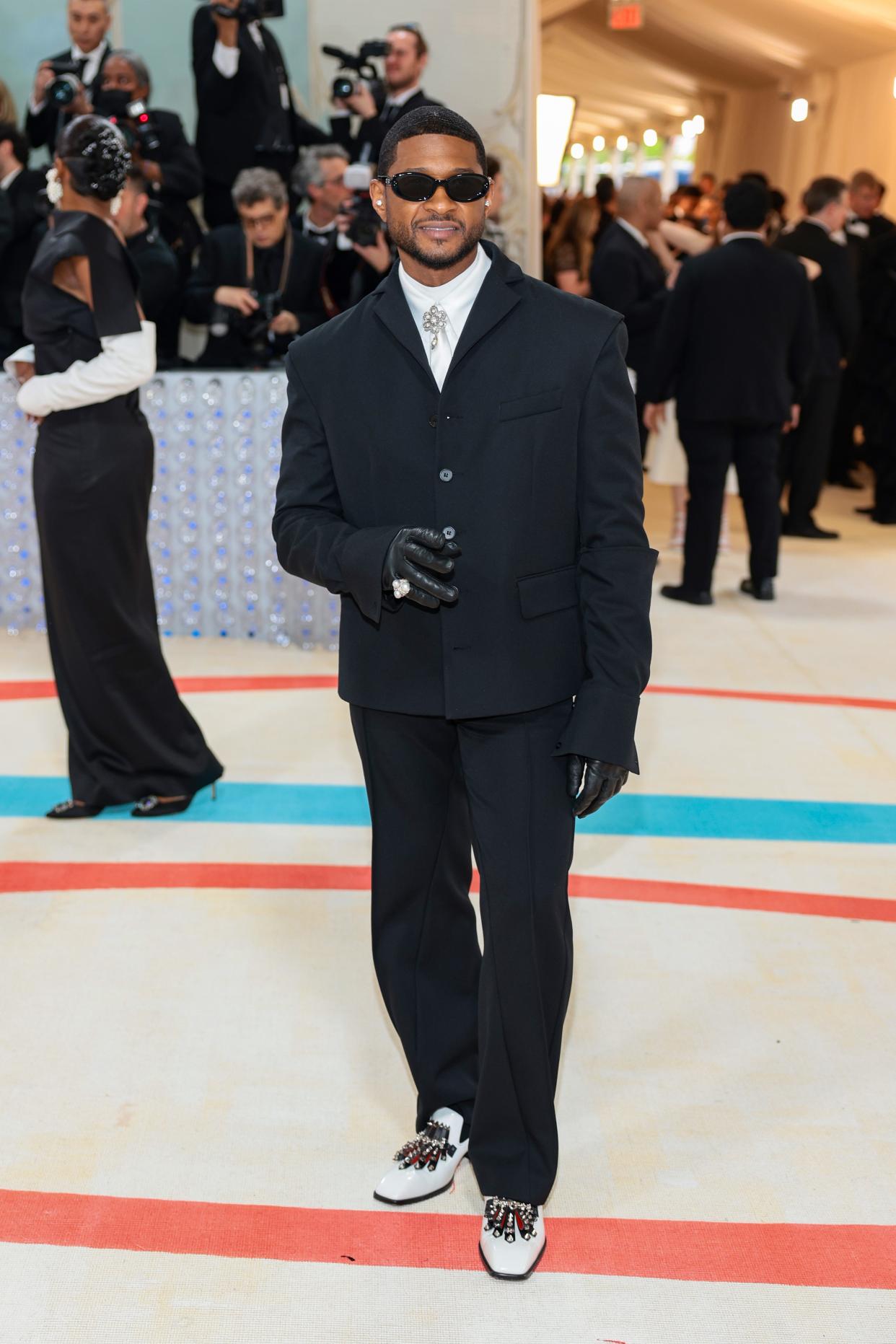 Wearing a black suit, black sunglasses, leather gloves and a cream tie paired with a glimmering tie knot broach, Usher embraced the theme.