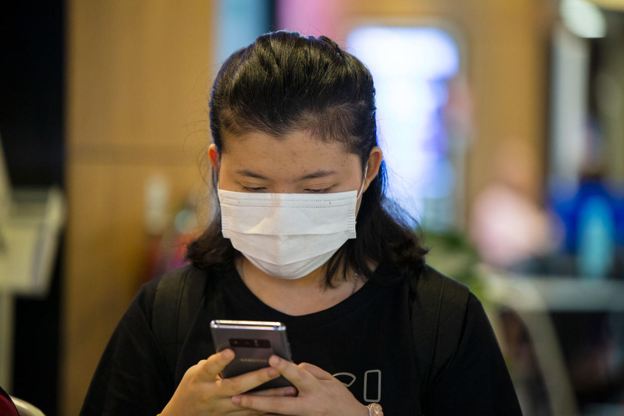 A woman wearing a face mask checks her phone. (PHOTO: Dhany Osman / Yahoo News Singapore)