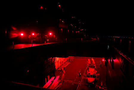 Maintenance crew transport an SH-60K Sea Hawk helicopter to an aircraft elevator in the red-lit hangar ready to raise it to the flight deck on Japanese helicopter carrier Kaga in the Indian Ocean, September 27, 2018. Picture taken September 27, 2018. REUTERS/Kim Kyung-Hoon