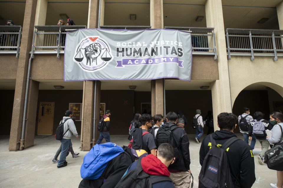 Students walk with backpacks on campus at Social Justice Humanitas Academy.